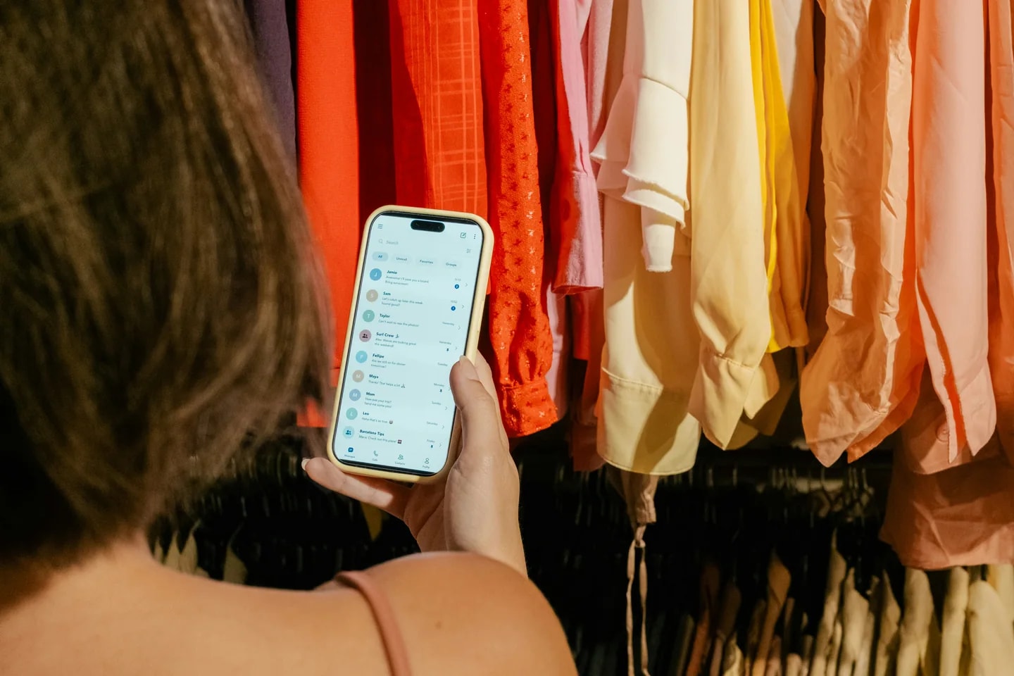 Consultation d’un smartphone devant un portant de vêtements