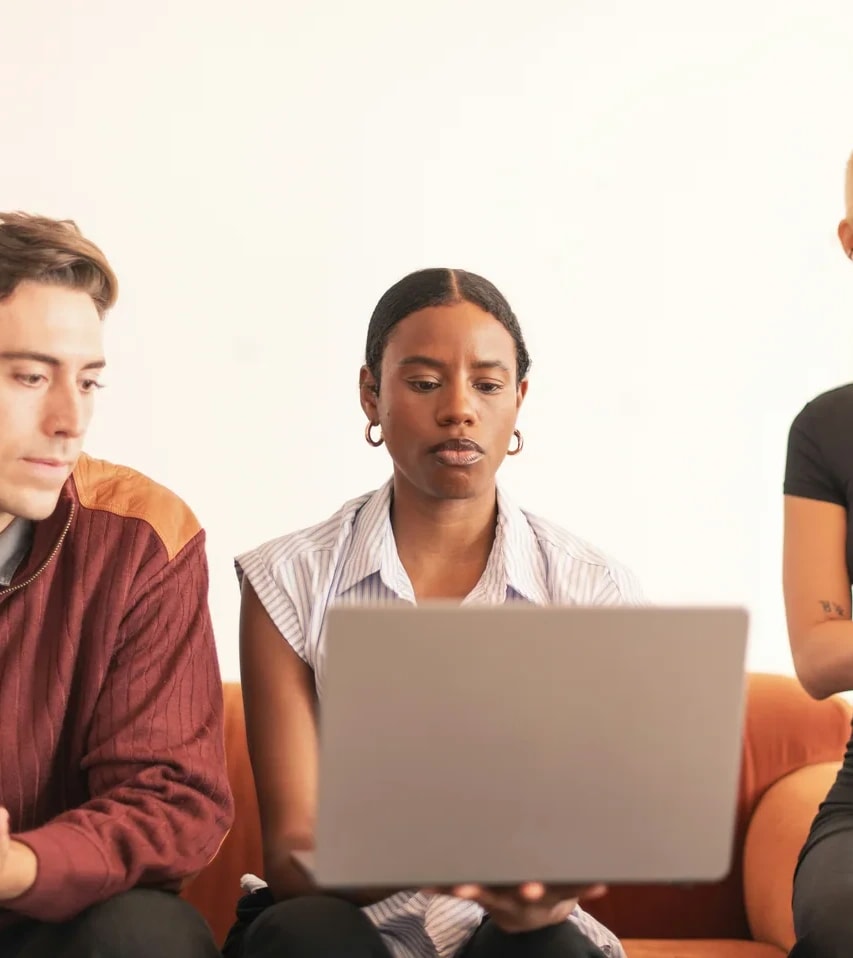Three people working around a laptop